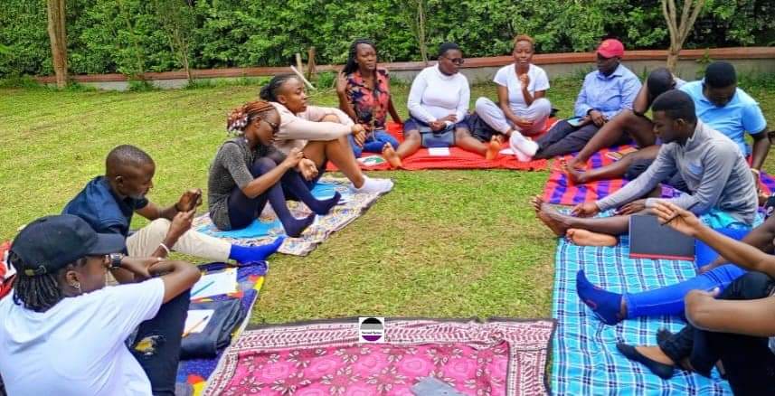 A group of people sitting outdoors on picnic blankets. 